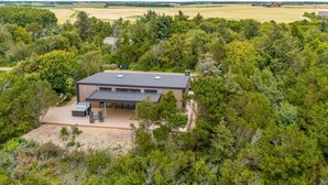 Een modern huis met een plat dak, omringd door dicht bos.