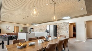 Een moderne keuken met een backsplash van baksteen, een centraal eiland en een eetgedeelte met een houten tafel en stoelen.