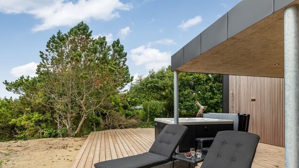 Een terras met twee ligstoelen, een jacuzzi en een houten dek.