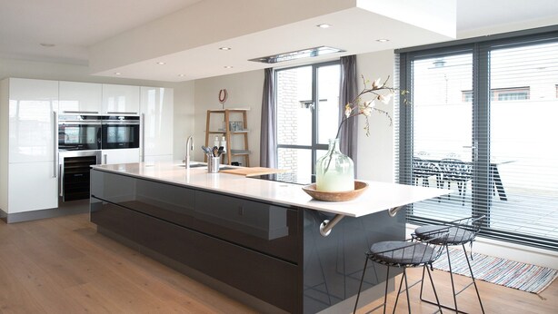 Una cocina moderna con una isla grande, electrodomésticos integrados y vistas al exterior.