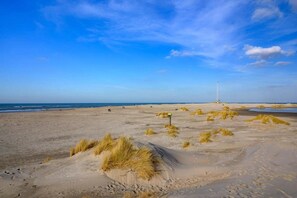 A sandy beach with dunes and a lighthouse in the distance. - Bungalow in Netherlands with Garden Terrace ('s-Gravenzande)