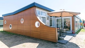Un edificio moderno con facciata in legno curvata, ampie finestre e una zona salotto esterna coperta.