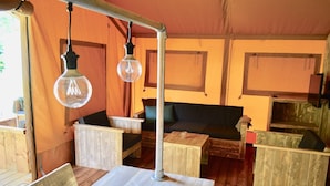 Un intérieur chaleureux avec une table en bois, des chaises et un canapé placés sous une structure ressemblant à une tente.