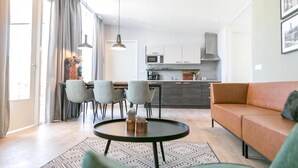 Een moderne woonkamer met een bank, een ronde salontafel en een eethoek met stoelen.