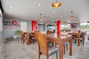 Un comedor amplio con varias mesas y sillas de madera, una planta en maceta y decoración inspiradora en la pared.