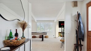 A room with a wooden floor, a white ceiling, a sofa, a coffee table, and a TV displaying 'Netflix'. - La Jolla Oasis | 4BR Luxury | Hot Tub | Close to Beach | Sleeps 12 (San Diego)