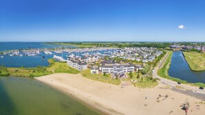 Una marina costera con varios barcos, una playa de arena y edificios residenciales.