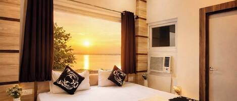 A hotel room with a large bed, wooden paneling on the walls, a ceiling fan, and a window with curtains.