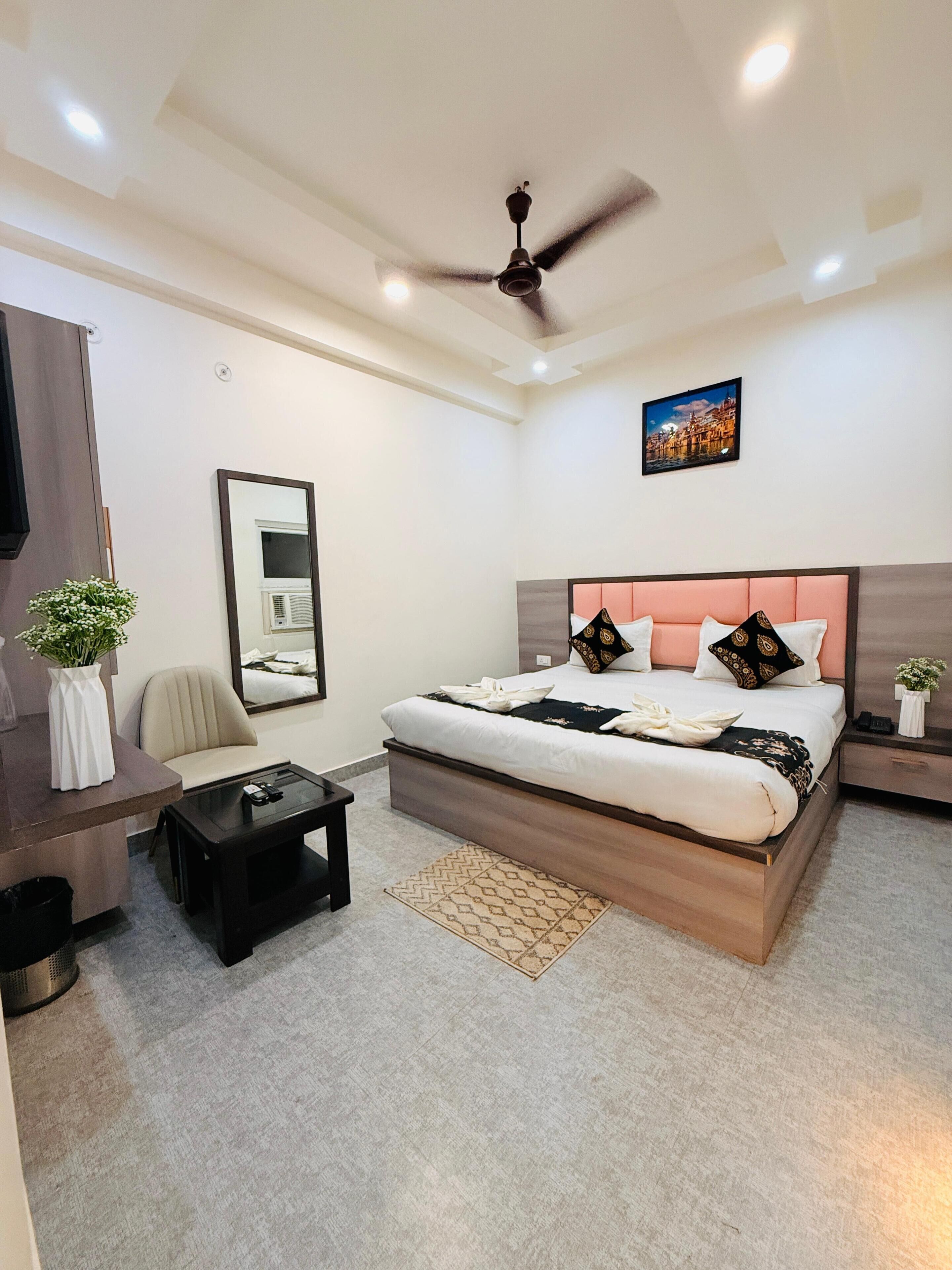 A bedroom with a bed, bedside tables, a desk, a chair, a ceiling fan, and a wall-mounted air conditioner.