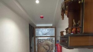 A narrow hallway with a wooden floor, a wall-mounted shelf with decorative items, and a door with a glass panel. - RUDRA GANGA HOTEL (Varanasi)
