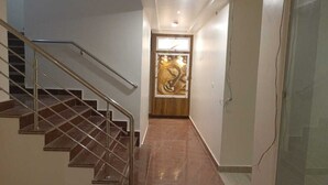A staircase leading to a room with a wooden door and a large abstract painting. - RUDRA GANGA HOTEL (Varanasi)