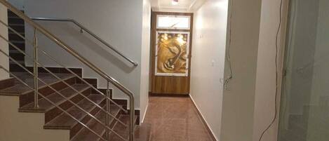 A staircase leading to a room with a wooden door and a large abstract painting.