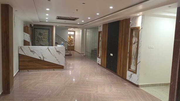 A modern hotel lobby with a marble reception desk, a staircase, and a statue. - RUDRA GANGA HOTEL (Varanasi)