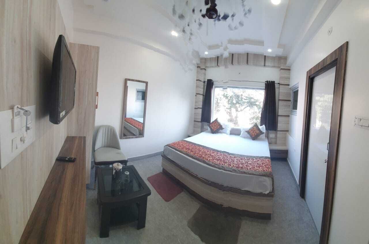 A bedroom with a curved bed, a flat-screen TV mounted on the wall, a chair, and a small table.
