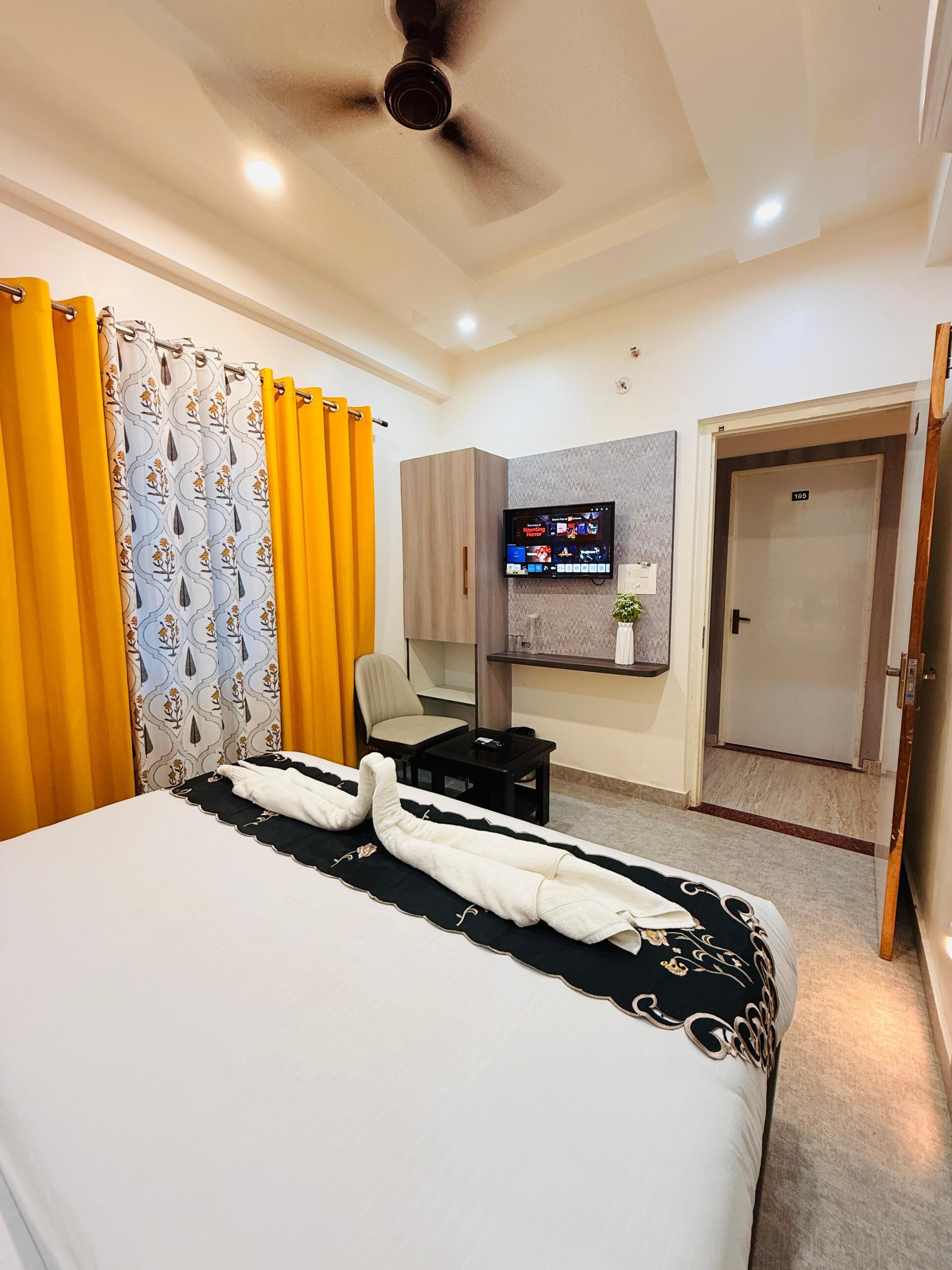 Habitació d'hotel amb llit, televisió, escriptori, cadira i armari.
