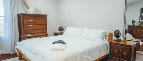 Un dormitorio con cama de madera, cómoda, mesita de noche y espejo.