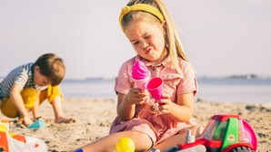 Ein Kind spielt mit Spielzeug am sandigen Strand.