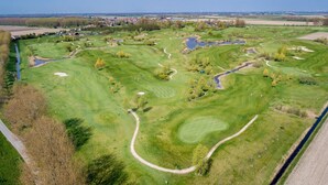 Eine Vogelperspektive eines Golfplatzes mit mehreren Abschlägen, Sandbunkern und Wasserhindernissen.