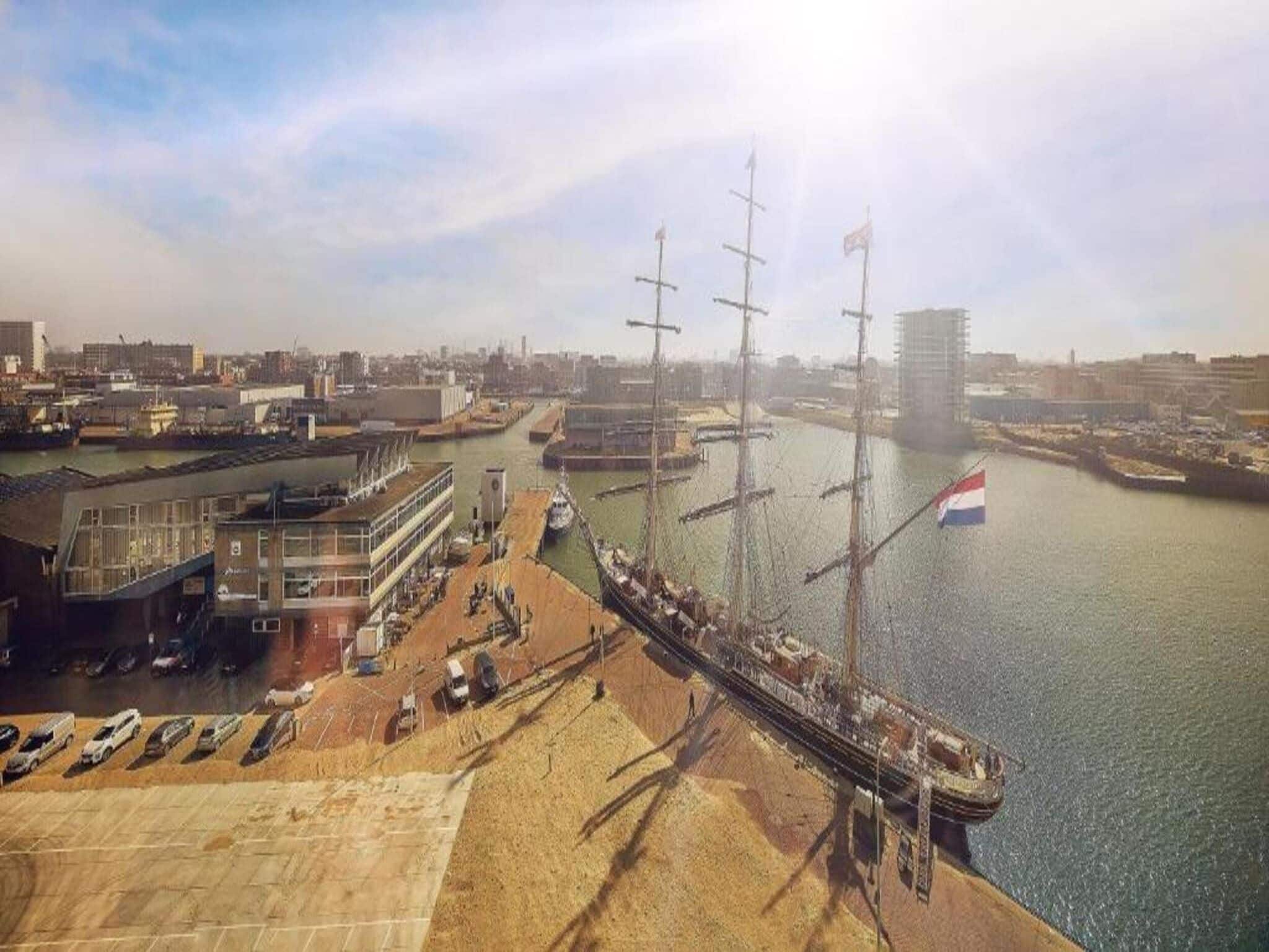 Zona costera con muelle, un edificio de fachada de vidrio y una bandera.