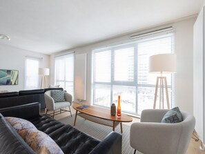 A modern living room with a sofa, armchairs, a coffee table, and a TV.