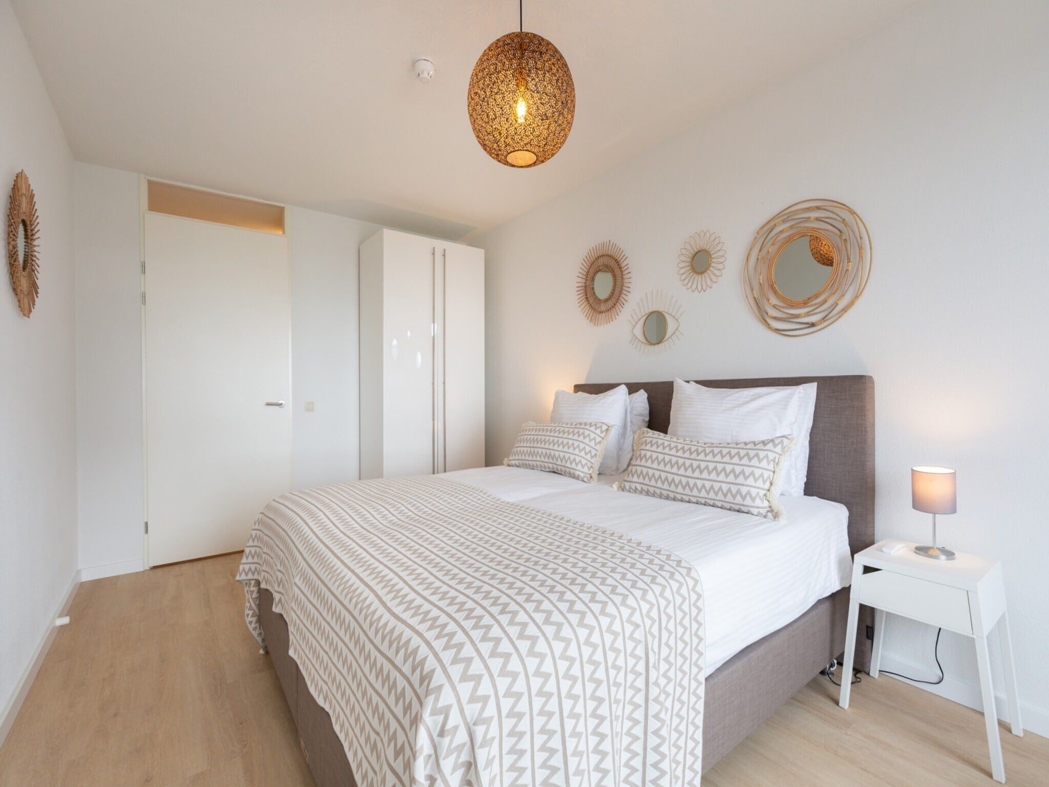 A bedroom with a bed, bedside table, and wall decorations.