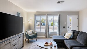 A living room with a large flat-screen TV, a sofa, a chair, and a coffee table with snacks and drinks. - Private Pool + Outdoor Oasis • 5mins to Old Town | Indianola Oasis by AvantStay (Scottsdale)