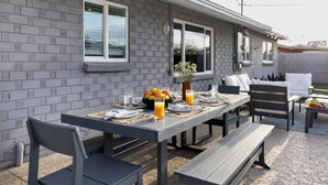 An outdoor dining area with a brick wall, a table set with plates, glasses, and a fruit bowl. - Private Pool + Outdoor Oasis • 5mins to Old Town | Indianola Oasis by AvantStay (Scottsdale)