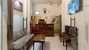 A reception area with a wooden desk, a sofa, and a bench. - Varanasi Rest House  (Varanasi)