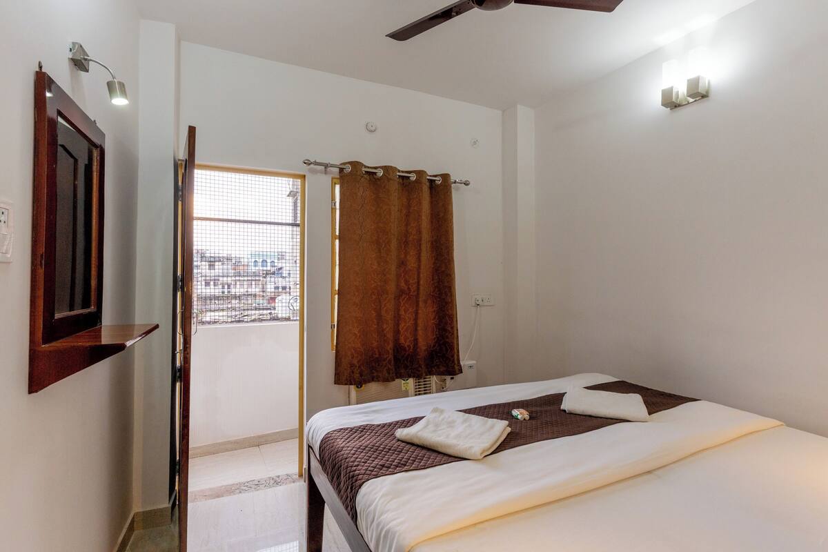 A bedroom with a bed, a ceiling fan, a window with curtains, and a door leading outside.