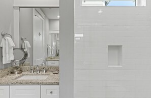 A bathroom with a granite countertop, a sink, a mirror, and a towel rack.
