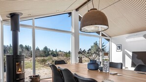 Un comedor moderno con una gran mesa de madera, sillas negras y un estufa de leña.