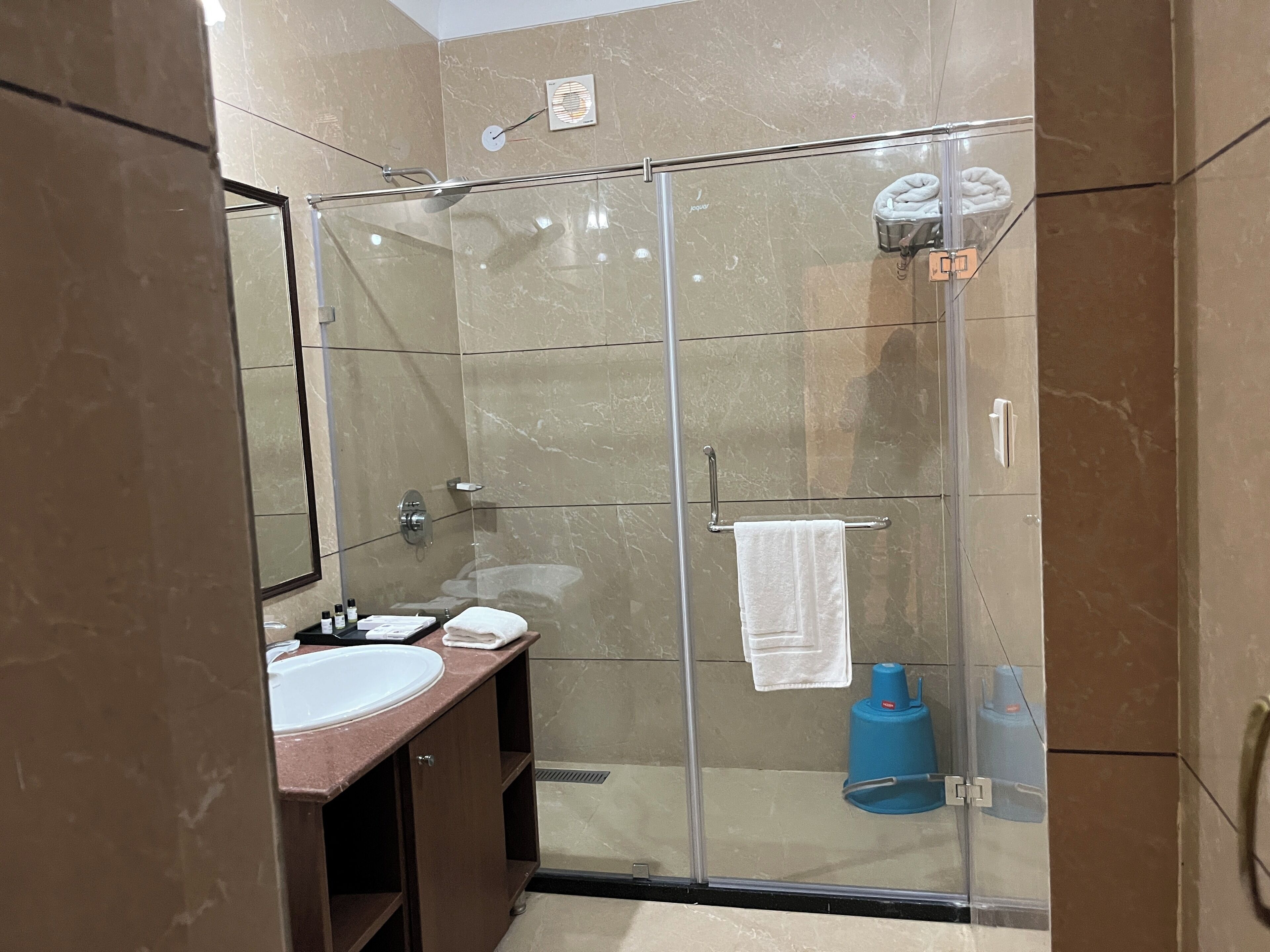Un baño moderno con ducha de vidrio, lavamanos y espejo.