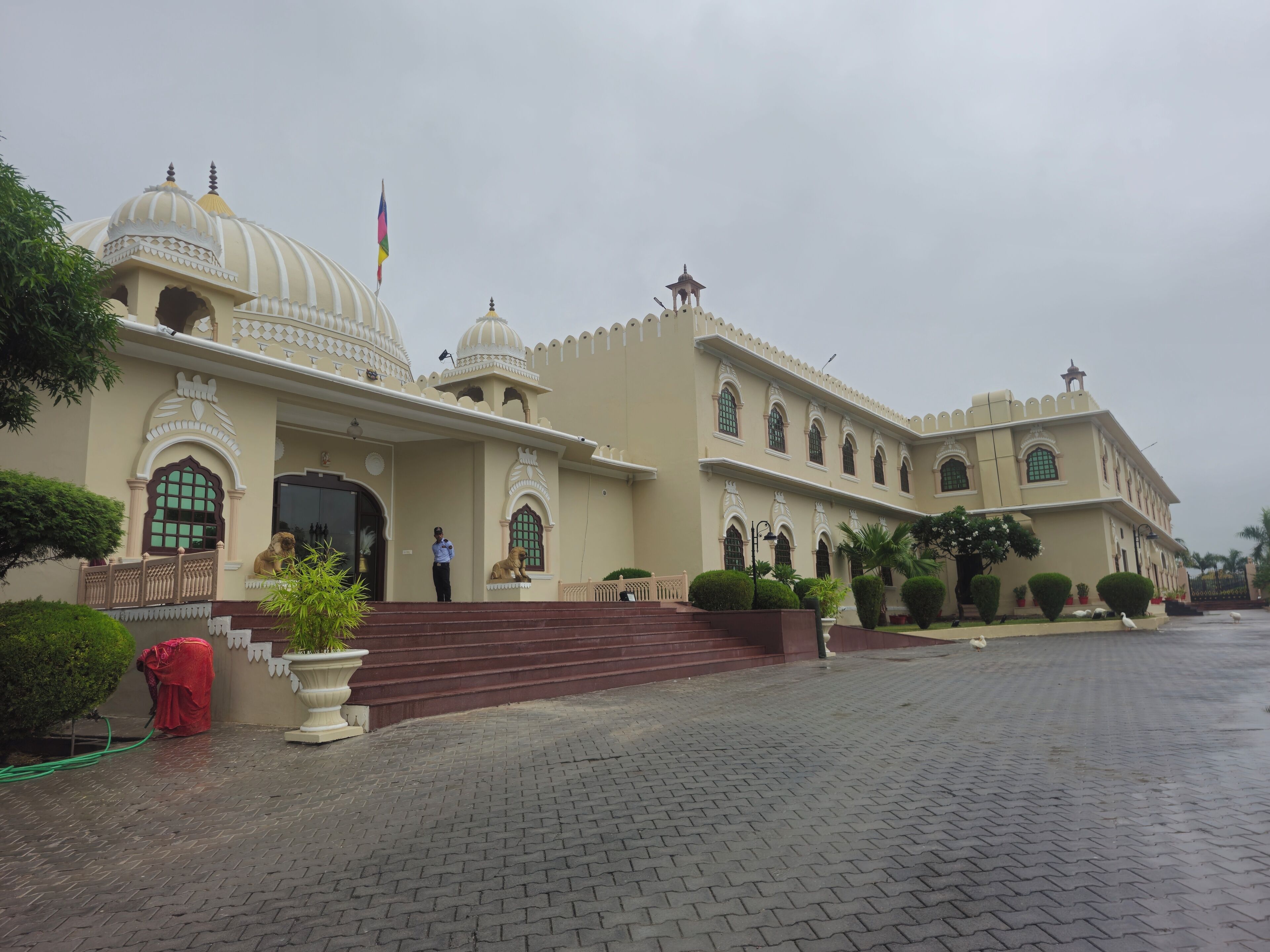 A large, historic building with multiple domes and arched windows, featuring a grand entrance with steps and a flag.
