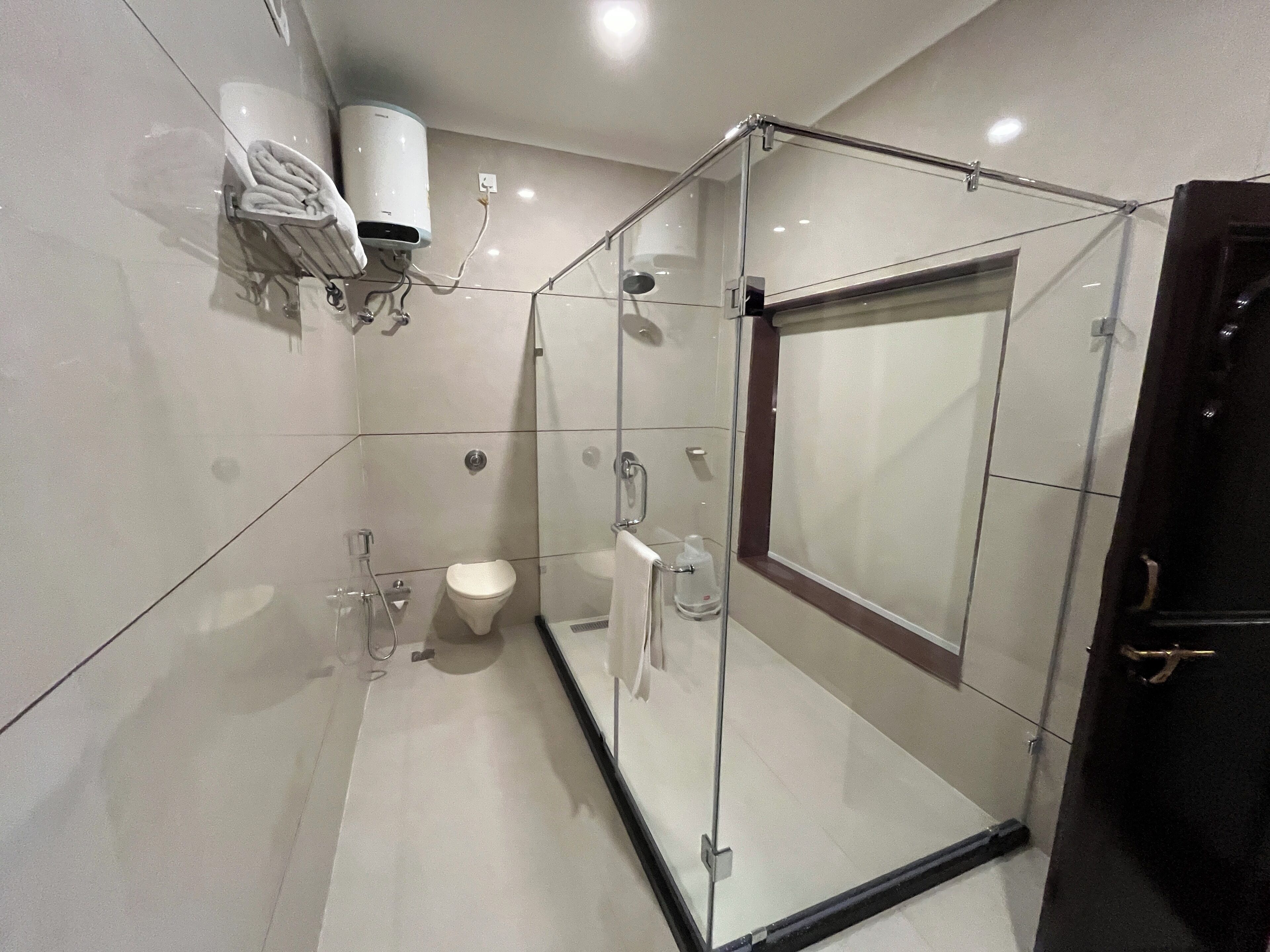 Un baño moderno con ducha envuelta en vidrio, inodoro y perchero para toallas.