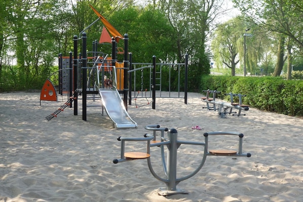 Une aire de jeux dotée de divers équipements, notamment un toboggan, des structures d’escalade et des appareils de musculation.