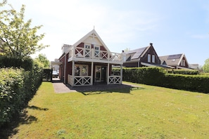 A two-story house with a balcony, a paved driveway, and a well-maintained lawn.