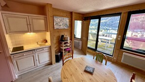 A cozy kitchen with wooden cabinets, a sink, and a dining table with chairs. - L'Oise 405 - Le Mont Dore 6pers (Mont-Dore)