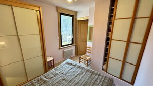 A small, compact room with a bed, a chair, a radiator, and a window. - L'Oise 405 - Le Mont Dore 6pers (Mont-Dore)