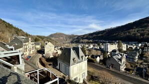 A town with traditional architecture, a main road, and a view of the surrounding hills. - L'Oise 405 - Le Mont Dore 6pers (Mont-Dore)