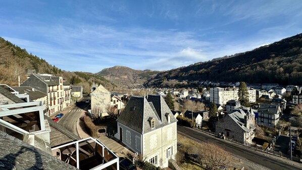 A town with traditional architecture, a main road, and a view of the surrounding hills.