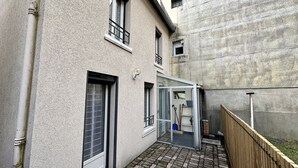 A residential building with a paved patio, a wooden fence, and a glass door leading to a garage.
