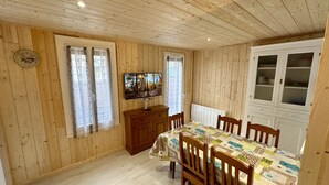 A wooden-paneled room with a dining table, chairs, a television, and a cabinet.