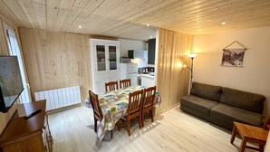 A compact living space with a dining area, kitchenette, and a sofa.