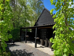 A wooden cabin with a sloped roof, surrounded by trees and a gravel path. - Apartment in Wageningen near Rhine River (Elst)