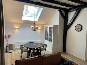 A dining area with a round table and chairs, a chandelier, a cabinet with glass doors, and a clock on the wall. - Apartment in Wageningen near Rhine River (Elst)