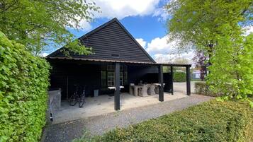A black building with a covered patio area, a bicycle, and a gravel path.