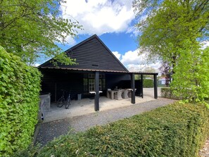 Un bâtiment noir doté d’un patio couvert, d’un vélo et d’un chemin de gravier.