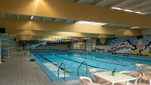 An indoor swimming pool with tiled floors, poolside chairs, and a colorful mural on the wall. - Holiday Home in Zevenhuizen near Delft (Zevenhuizen)