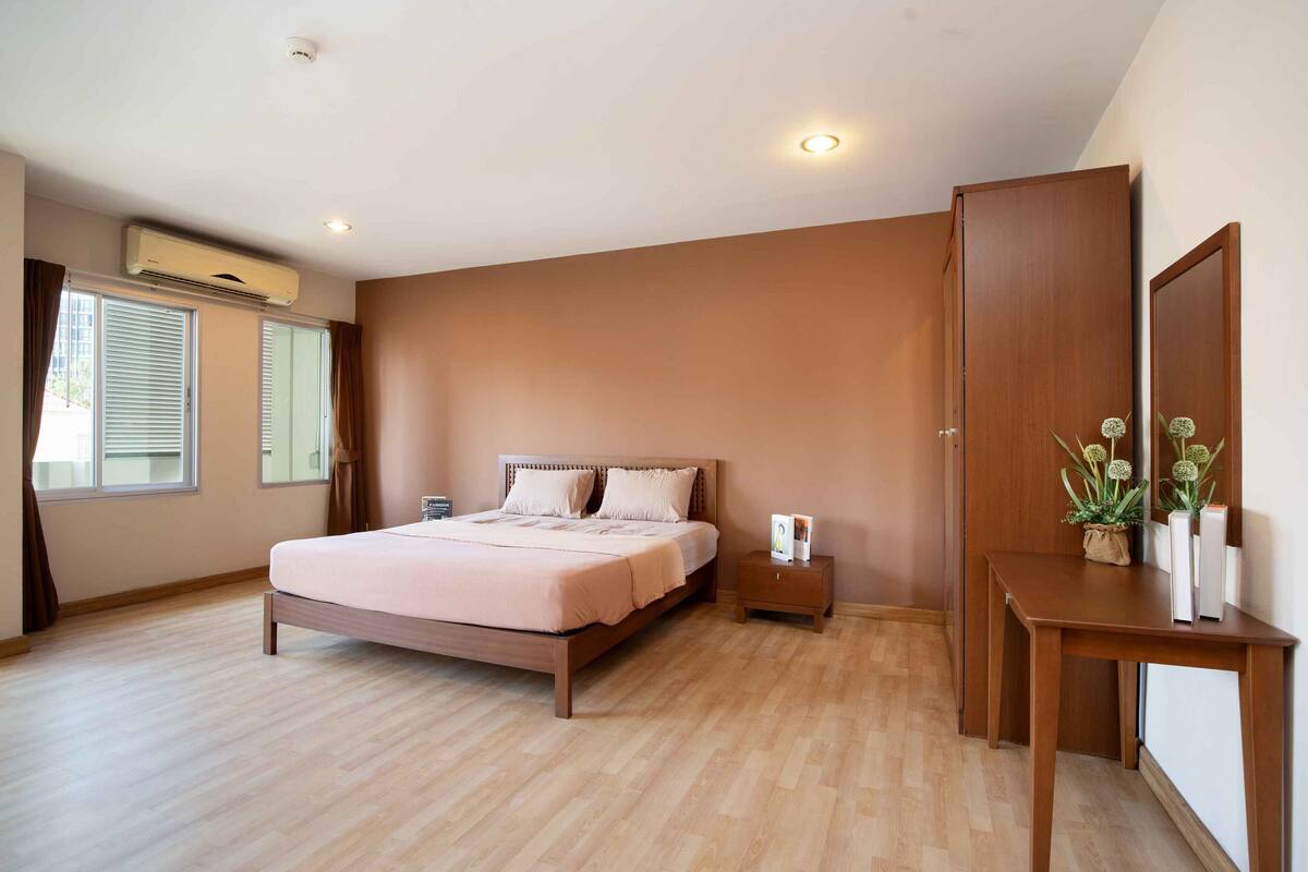 A bedroom with a bed, bedside table, nightstand, and a mirror.