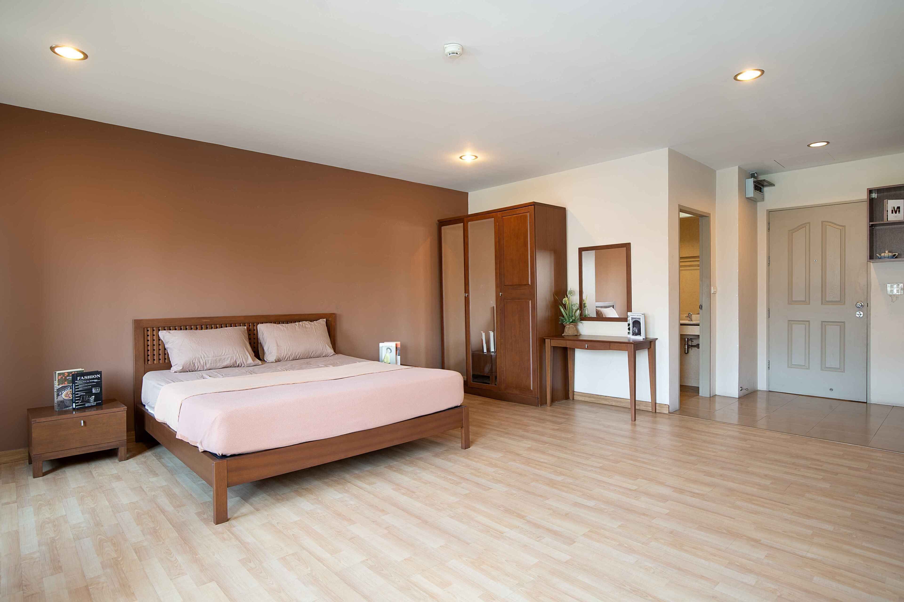 Un dormitorio con cama, mesita de noche, armario y una pequeña mesa con una planta.